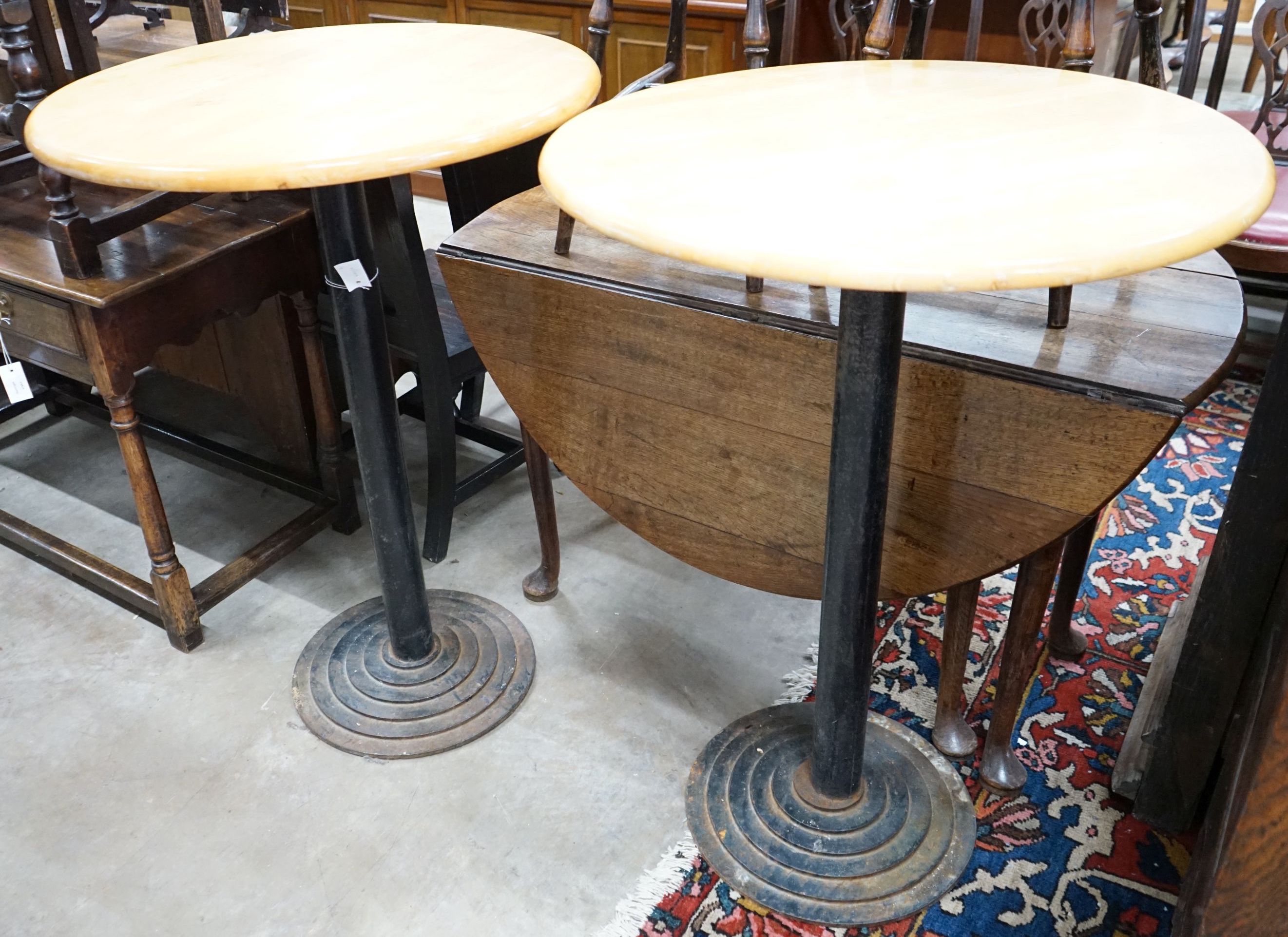 A pair of circular beech and iron pub tables, diameter 74cm, height 104cm